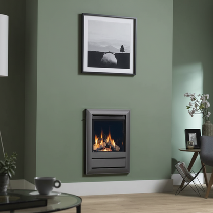 A modern wall-mounted electric fireplace with a dark gray frame and glowing orange flames, set into a sage green wall in a living room setting.