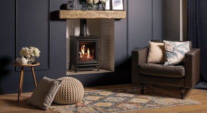 Chesterfeild Gas Stove in Cozy living room with a fireplace, armchair, and decorative items.