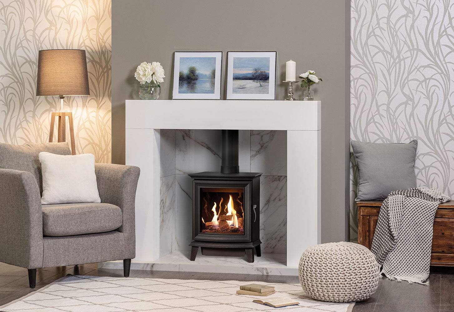 Gazco Chesterfield Gas Stove in Living room with a Taupe fireplace, gray armchair, and decorative items.
