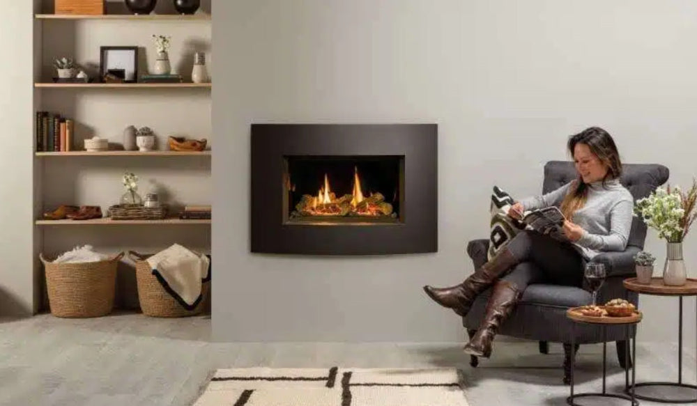 Woman sitting in a chair reading a book in front of a modern fireplace.