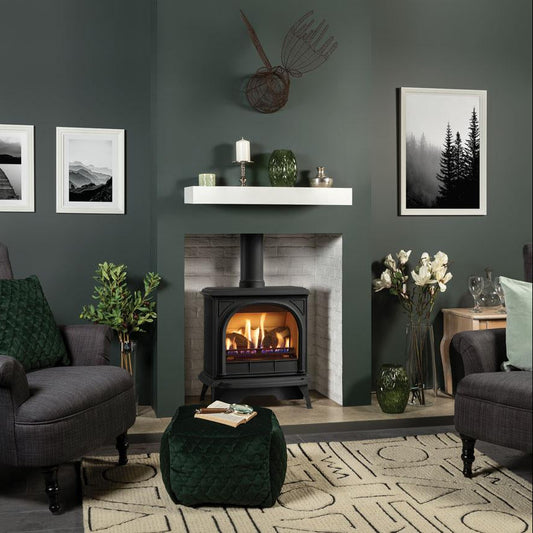 Cozy living room with Gazco Huntingdon 30 Gas Stove fireplace, gray chairs, and decorative elements in forest green room.
