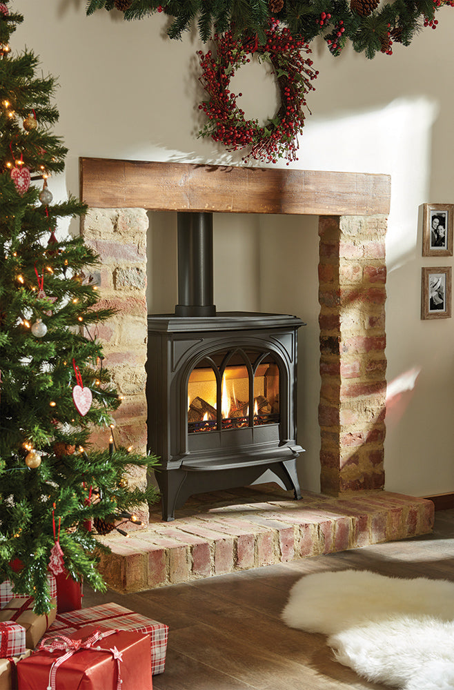 Cozy living room with a lit fireplace, Christmas tree, and wreath.