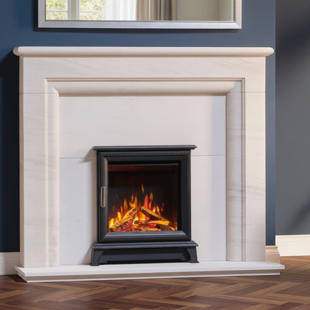 A modern black Wildfire Ravel 400e Electric Inset Stove Fire in Anthracite, set within a white marble fireplace mantel, shown in a styled room with dark blue walls and herring bone walnut wood flooring.