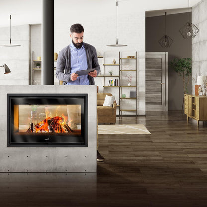 Man using a tablet in a modern living room with a Lacunza Nickel Double Sided Wood Burning Stove Range for Ireland