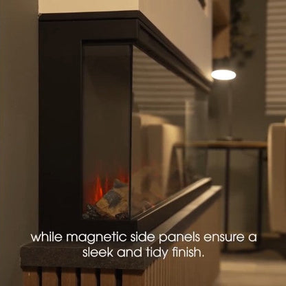 A modern black electric Atmos Fire FX Versa fireplace insert with glass side panels and faux logs, shown in a dimly lit living room setting with overlaid text about magnetic side panels.