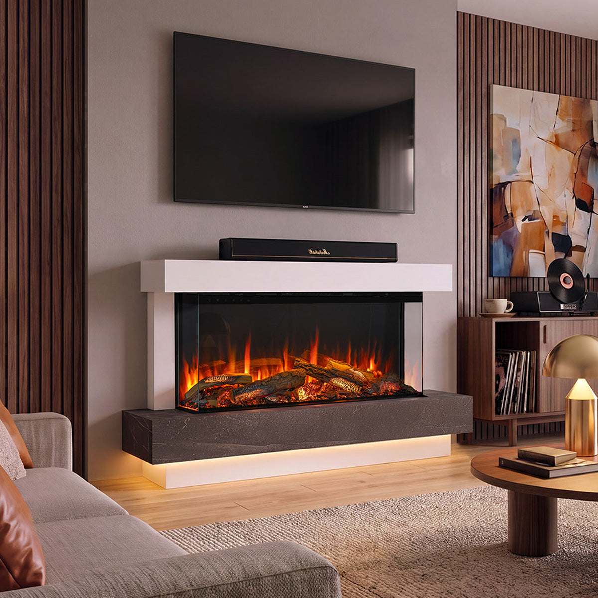 A modern wall-mounted Turin 120 electric fireplace with a white floating mantel, dark stone base, and glowing faux logs, installed in a contemporary living room with a TV above and a sofa nearby.