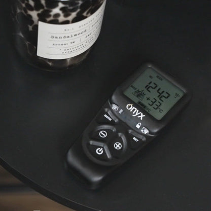 Digital Thermostatic Onyx Remote Control Handset on a dark surface with a leopard print candle in the background from the Onyx Liv 3 Gas Stove High Efficiency Gas Stove Ireland Contemporary Log Effect Gas Stove