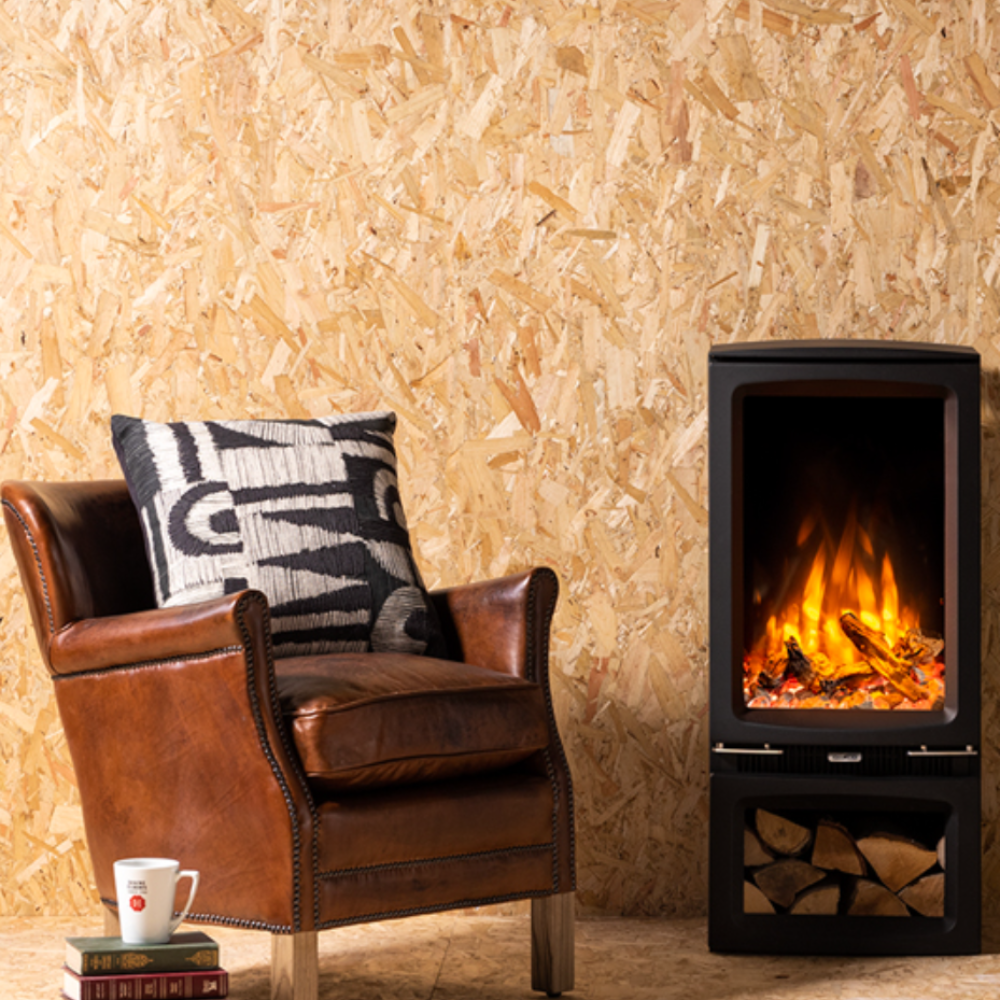 Gazco Vogue T with Brown leather armchair with a decorative pillow in front of a lit electric fireplace against a wooden paneled wall.