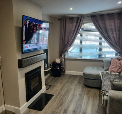 Vitae 5kw Landscape Glass Door Solid Fuel Wood Burner Inset Stove & Flue Bundle (9m Flue Kit) fitted into a wall setting Irish Living room in a calm mocka tones, Tv fitted above with a Geo Cast Dark Oak Beam and custom black polished granite besoke hearth stove