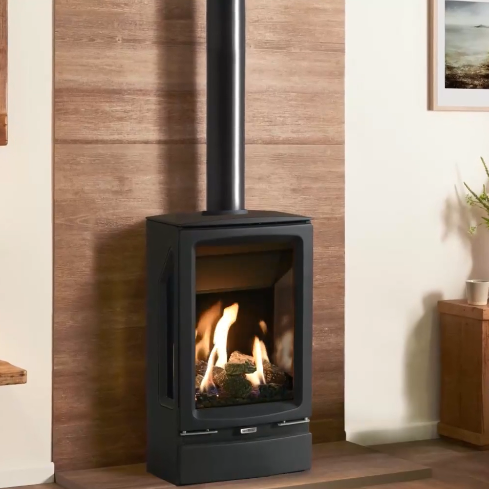 Gazco Midi T Modern freestanding stove with flames inside, placed against a wooden wall in a room.
