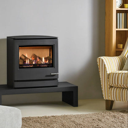 Modern Gas Yeoman CL8 gas stove with flames inside, placed on a black stand in a living room setting.