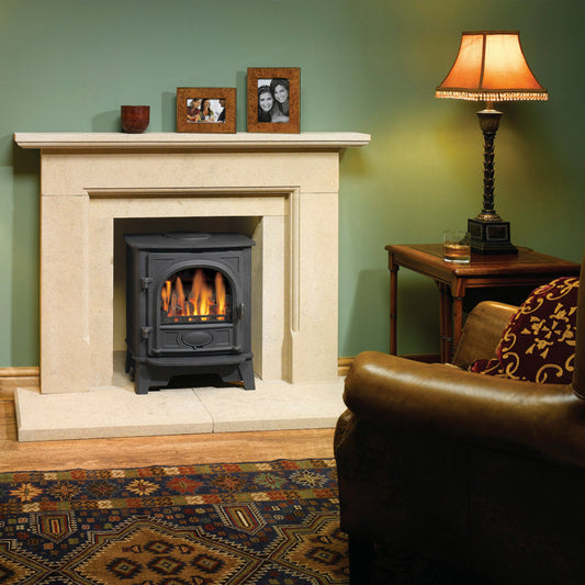 Gazco Stockton 5 Balanced Flue Gas Stove in Cozy living room with a lit fireplace, lamps, and framed photos on a mantel.