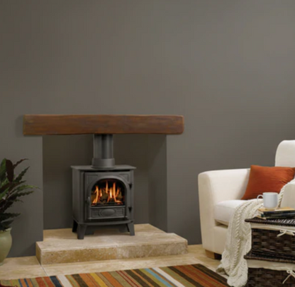 Gazco Gas Wood-burning Gas stove in a living room with a white armchair and decorative items.