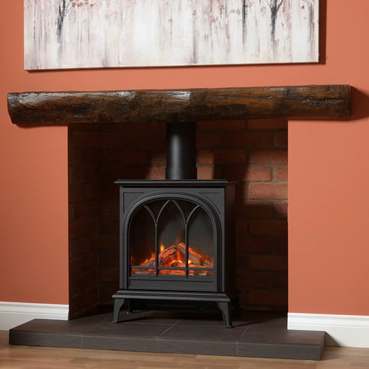 Black Wildfire 400TE freestanding stove with glowing interior in a fireplace setting with wooden mantel and abstract painting.